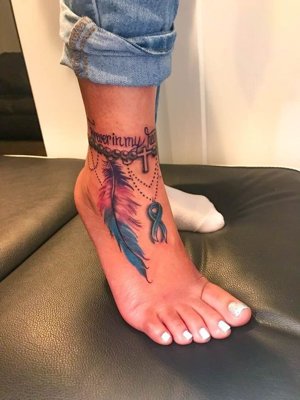 Tatouage plume coloré bleu et rose sur la cheville